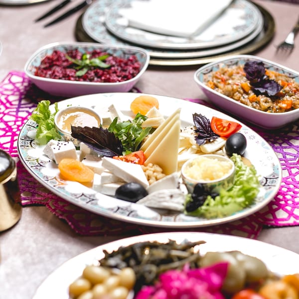 A Pyramid Cafe cheese platter with honey, olives, tomatoes, dried apricots, and basil, surrounded by other Mediterranean dishes.