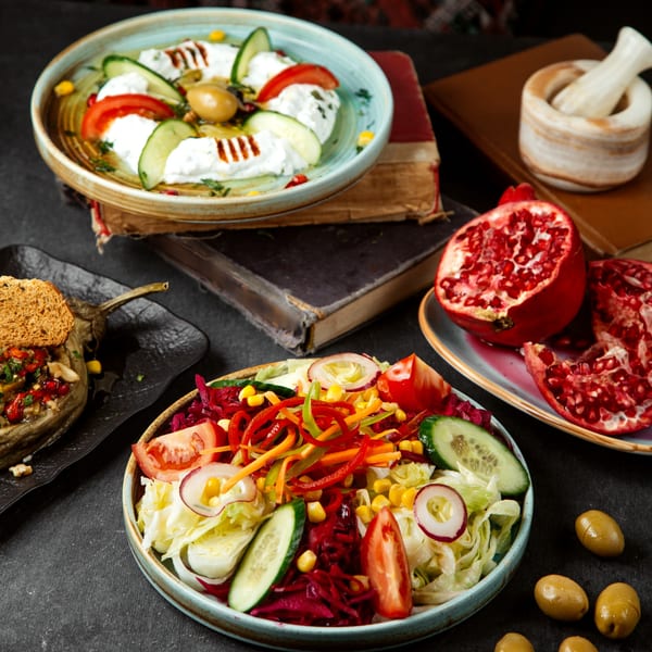 A vibrant spread of Mediterranean dishes, including a fresh salad, yogurt dip, and stuffed eggplant.