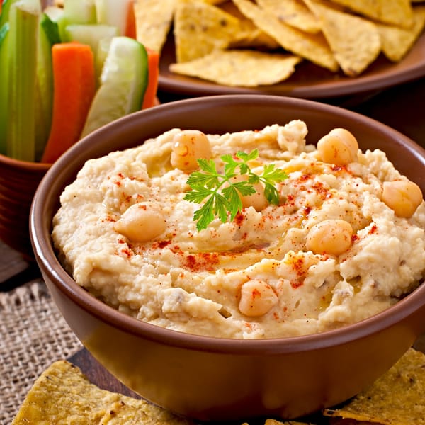 Creamy hummus topped with chickpeas, paprika, and parsley, served with fresh vegetables and pita chips.